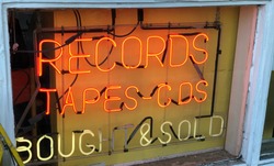 Vintage neon sign in record store window - records, tapes, cds bought and sold