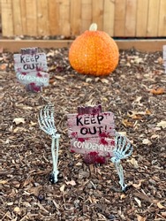 Yard is decorated for Halloween with a makeshift cemetary and pumpkins
