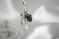 A silver earring with a pearl, leaves and a silver cone
