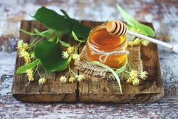 Selective focus. Linden honey in a jar. Leaves and flowers of linden. Freshly linden honey.