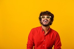 Positive bearded man laughing out loud, chuckling and hysterically laughing with anecdote, having fun. Indoor studio shot isolated on orange background