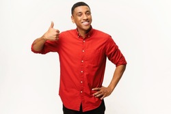 Cheerful African-American guy in red shirt showing thumb up isolated on white. Smiling multiracial man showing approval gesture at the camera, likes it