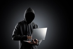 Cybercrime, hacking and technology crime. no face hacker with laptop on black background with clipping path.
