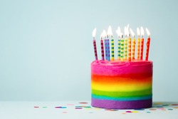 Rainbow colored birthday cake with brightly colored birthday candles