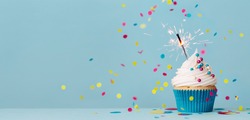 Birthday party background with birthday cupcake, celebration sparkler and colorful falling confetti