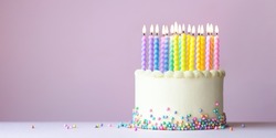 Rainbow birthday cake background with colorful rainbow candles 