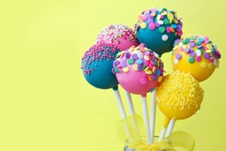 Colorful cake pops on a yellow background