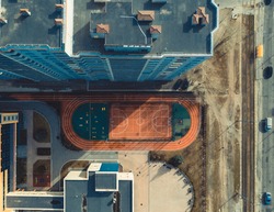 a modern school with a basketball court next to a multi-storey residential building. top view of the sports ground next to the gymnasium. school in eastern europe. 4k Aerial
