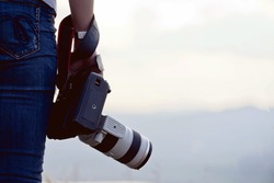 photographer holding camera, close-up. Back view, Selective focus. sunset  of background.
