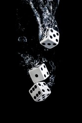 Dices sinking in water with bubbles on black background in water with bubbles on black background