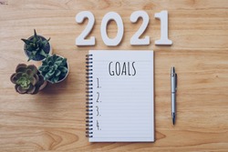 New year 2021 goals list. Office desk table with notebooks and pancil with pot plant.