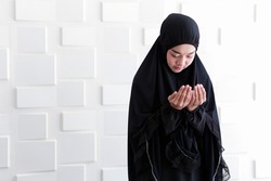 Asian beautiful cute Muslim lady praying and thinking to god of Islamic - Allah in mosque. Hands of Islam woman holding up to air for peaceful  - dress in Muslim cloth - Hijab. Bangkok Thailand Asia