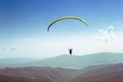 paraglider flies. paraglider over the tops of the mountains in summer sunny day.