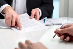 Signing a contract or agreement. Banker or lawyer showing client the line for autograph in a document paper. Business man with a customer in office making deal. Employee hired.