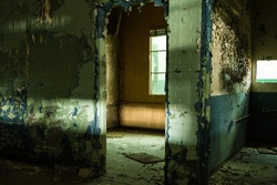 Looking through open doorway in an abandoned factory with peeling paint in a depressed urban area