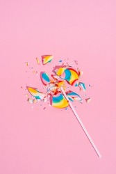 Broken Colorful lollipop on pastel pink background, top view. Candy colours. Minimal Sugar detox, junk food and party concept.