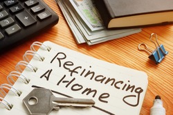 Conceptual photo is showing printed text refinancing a home