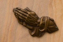 religious symbol of praying hands on a memorial tomb stone