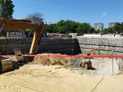 construction site, excavators are digging a foundation pit for a large building.