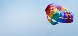 multi-colored parachute in LGBT colors as a symbol of freedom against the background of the sunny sky, copy space.