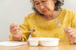 Unhappy Asian senior woman anorexia and say no to ready meals, Elderly home alone and bored food and no appetite