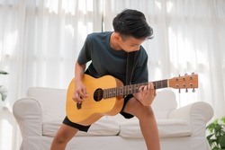 Portrait of a Asian happy smiling boy having fun playing guitar Music concept, kids music school. Rock concert,  Music for kids and toddlers concept