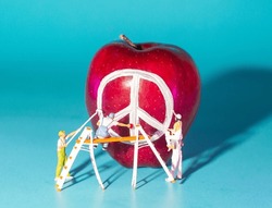 miniature people is drawing peace sign  on an apple