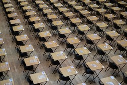 Hall with empty wooden desks and plastic chairs, ready to be used for examination purposes.
