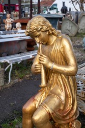Gold statue amidst other ephemera at reclamation yard. Photographed November 2020.