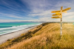 Distance and direction signpost on a beautiful, sunny beach. McCracken's Rest, Southland, New Zealand.