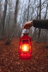 A red kerosene lamp burns in a dark forest. The lamp illuminates the road in a dark forest.