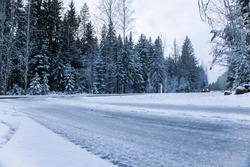 Car drives on empty snowy road in winter forest. Beautiful frosty white landscape at dawn.