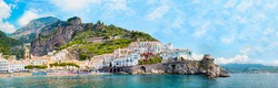 Panoramic view, aerial skyline of small haven of Amalfi village with tiny beach and colorful houses located on rock. Tops of mountains on Amalfi coast, Salerno, Campania, Italy.