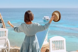 Happy woman enjoys view of coast of Red Sea. Panoramic views of blue sea with white yachts, boat and coastline. Beautiful landscape, aerial view, Sharm El Sheikh, Egypt. High quality photo