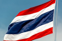 A large Thai flag flutters in the blue sky. The flag of Thailand has three colors. blue white and red independence flag constitution day national holiday text area