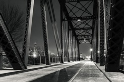 Black and white night photograph from under the Cherry Avenue Z-2 asymmetric bob-tail railroad swing bridge looking towards the Chicago skyline.