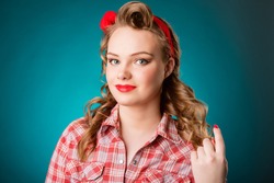 Closeup young pretty pinup girl red button shirt  looking at you camera  teal color background retro vintage 50's style. Human emotions body language