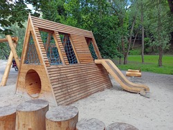 Children's playground equipped with wooden swings and slides. A modern children's slide made of wood and natural materials.