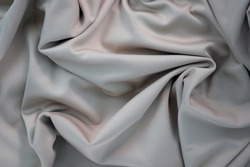 Draped canvas close-up. Abstract polyester fabric background. Top view of fabric with many folds. waves of satin material, shiny texture. 