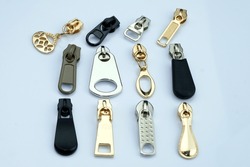 Metal runners of different shapes on a white background. Runners in gold, black and gray for clothing. A collection of zipper accessories for clothes.