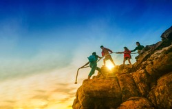 Young asian couple climbing up on the mountain,hiking and team work concept, Sunset background.
