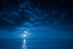 This photo illustration of a deep blue moonlit ocean and sky at night  would make a great travel background for any travel or vacation purpose.