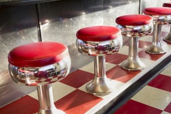 Warm morning sunlight highlights the simple but beautiful design of this classic diner counter with it's galvanized steel counter, bright chrome seats with red padding and bright red tiles.