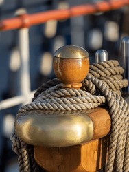 Close-up shot of a brass and wooden bollard on a historic sailing ship in the evening sun