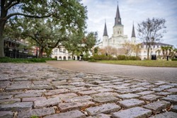 Cobblestone street in view in Jackson Square, French Quarter, New Orleans, with the St. Louis Cathedral in the distance. Shallow focus on the cobblestone street for effect.