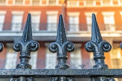 Close up of the beautiful iron fence in Jackson Square, in the French Quarter, New Orleans. The historic Pontalba building is blurred in the background.