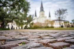 Cobblestone street in view in Jackson Square, French Quarter, New Orleans, with the St. Louis Cathedral in the distance. Shallow focus on a street stone for effect.