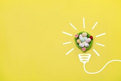 Idea symbol in the form of a painted light bulb with decorative Easter basket with eggs inside on a yellow background. Easter time