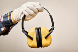 Worker's hand giving protective earphones: hearing protection and labor protection concept.