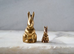 Small brass rabbit figurines on gray marble. From more to less. Image of difference.